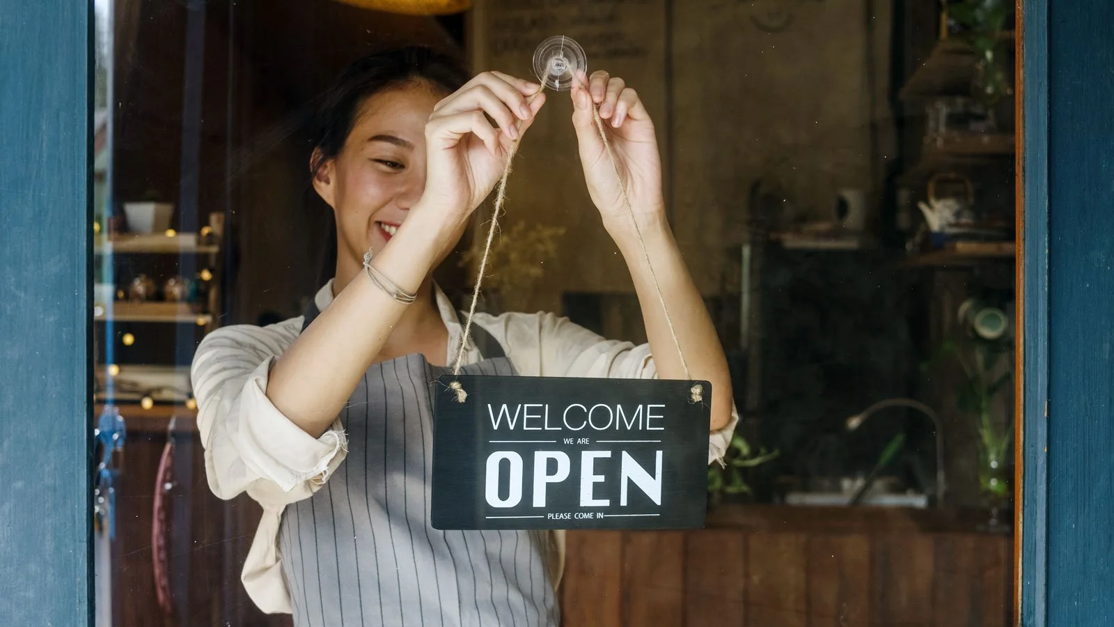 Young manager girl changing a sign from closed to open sign on door cafe
