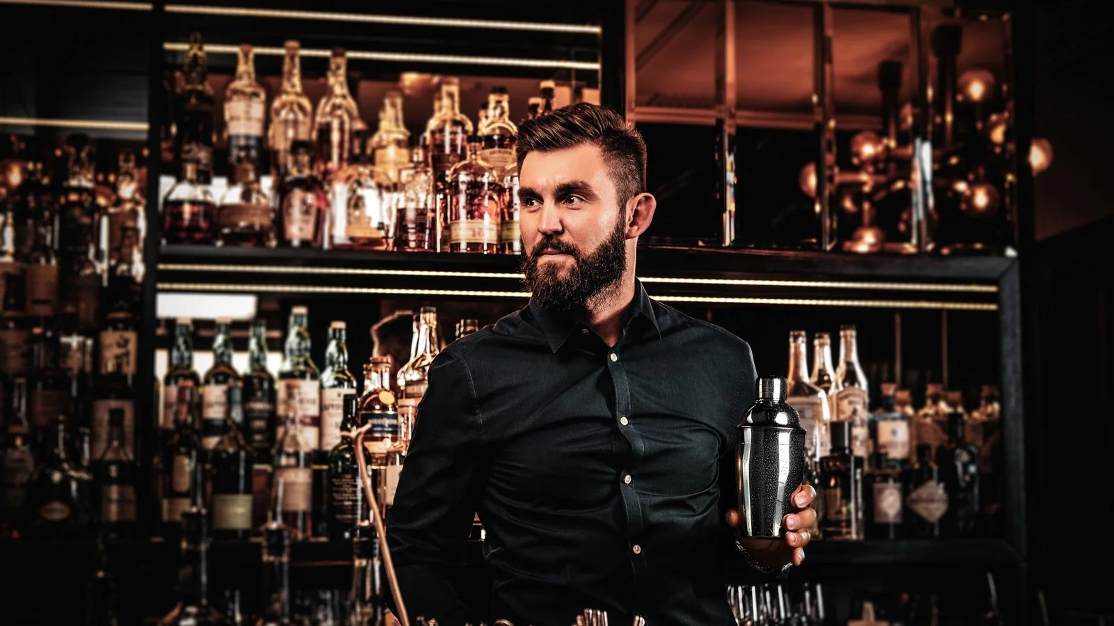 Elegant happy bar owner is making special drink for his customers at his own bar