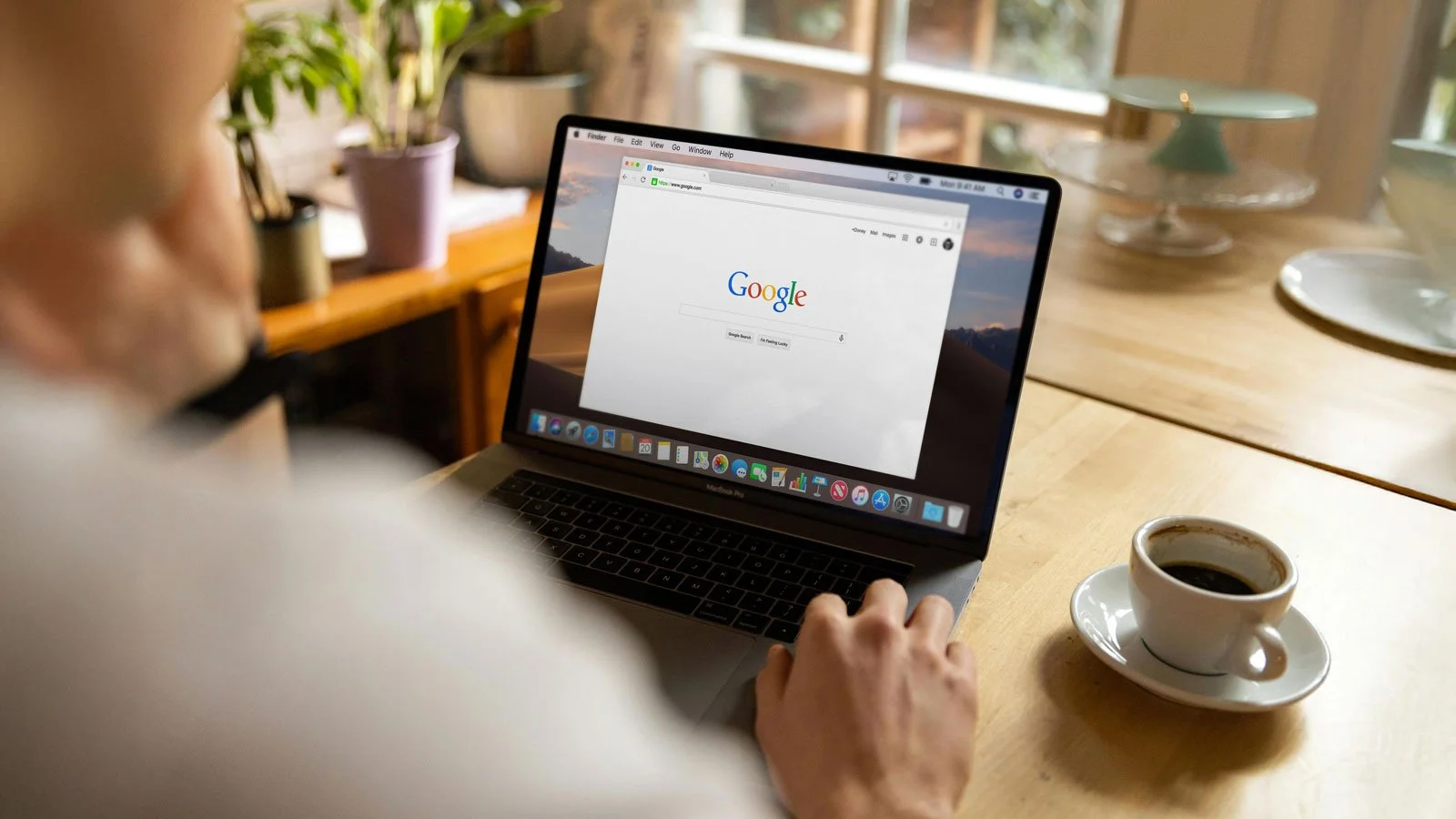 A Person Using a Laptop to search Google and enjoying a coffee